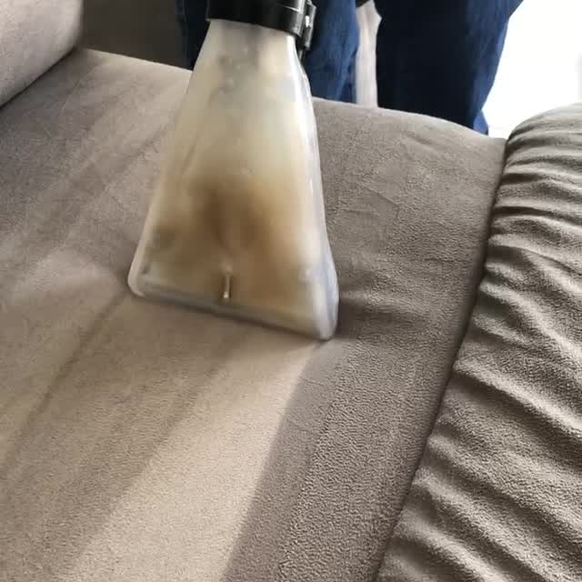 L'embout d'extraction transparent passant sur l'assise d'un canapé et aspirant l'eau sale.