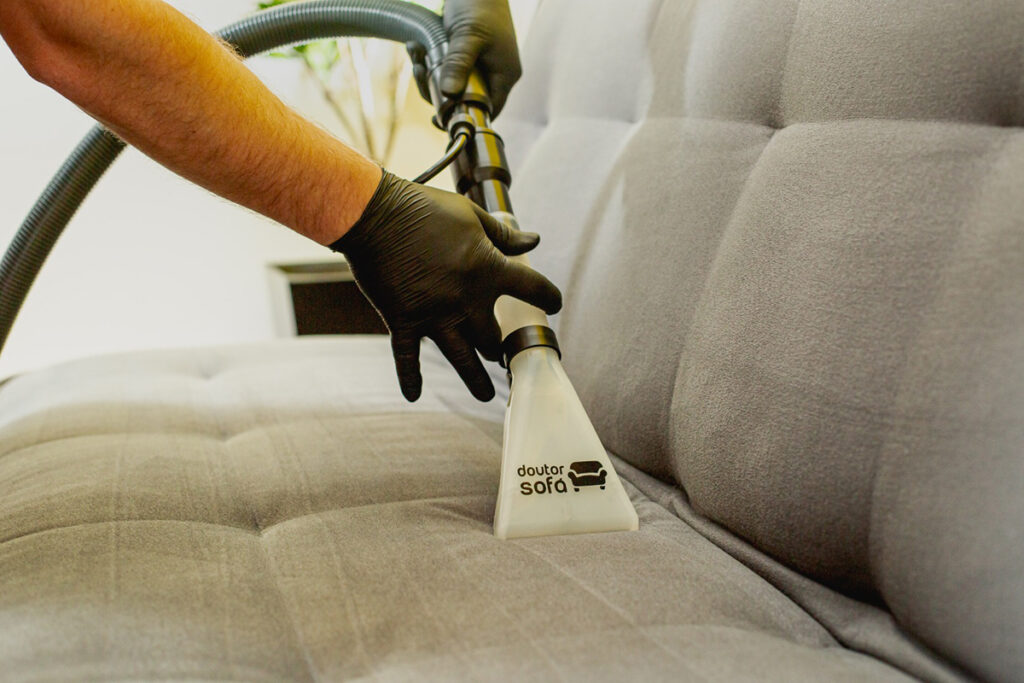 Buse d'extraction à la marque Docteur Sofa passée sur l'assise d'un canapé gris.